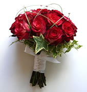 Bouquet confeccionado com rosas importadas de cor laranja, folhagens e cetim laranja